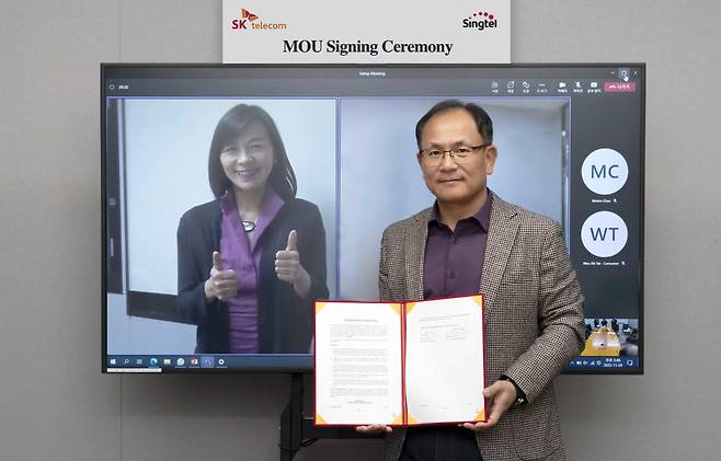 하민용 SKT 최고사업개발책임자(CDO)(오른쪽)와 아나 입(Anna Yip) 싱텔 고객 담당 CEO(화면 왼쪽)가 업무협약을 맺고 있다.