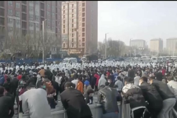 지난 23일 중국 허난성 정저우 폭스콘 공장에서 수백명의 노동자들이 시위를 벌인 가운데 방호복을 입은 보안요원들과 대치하고 있다. AP뉴시스