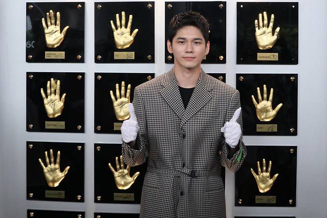 배우 옹성우가 본인 핸드프린팅(오른쪽 상단)을 부착한 뒤 사진촬영을 하고 있다.
