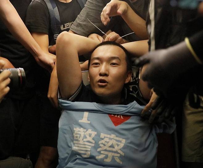 푸궈하오가 2019년 8월13일 홍콩의 첵랍콕 국제공항에서 반중 시위대에 둘러싸여 있다. 중국 관영매체 <환구시보> 기자로 취재를 나온 그는 “홍콩 경찰을 사랑한다”는 티셔츠를 가지고 있다가 시위대로부터 폭행을 당했다. 연합뉴스