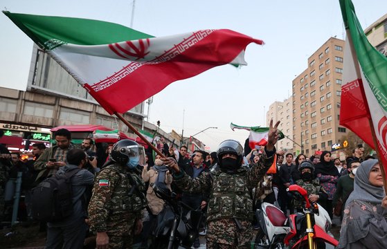 시위를 진압하는 이란의 경찰이 월드컵에서 이란이 웨일스에 승리하자 지난달 25일 수도 테헤란에서 깃발을 흔들며 기뻐하고 있다. AFP=연합뉴스