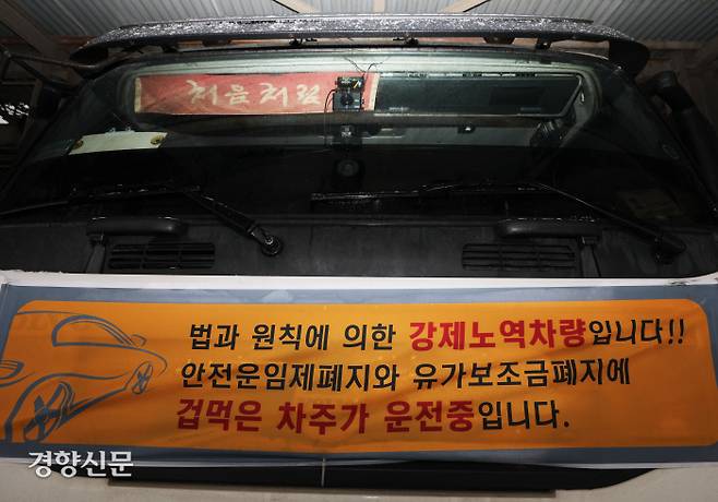 화물연대 파업을 지지하는 비조합원 화물기사 조동현씨가 자신의 차량에 ‘강제노역 차량입니다’라는 문구 등을 적은 현수막을 매달고 운행하고 있다. 한수빈 기자