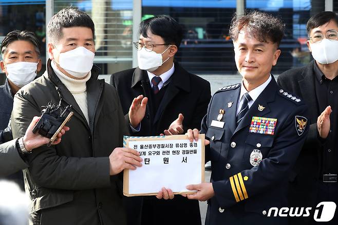 행정안전부 경찰국 신설에 반대하며 전국경찰서장(총경) 회의를 주도했던 류삼영 총경(전 울산중부경찰서장)이 8일 오후 서울 서대문구 경찰청에서 열린 징계위원회에 출석하기 앞서 직장협의회 동료 경찰들의 탄원서를 전해 받고 있다. 2022.12.8/뉴스1 ⓒ News1 민경석 기자