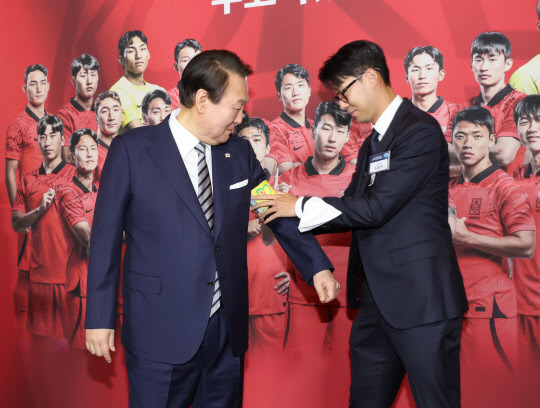 8일 청와대 영빈관에서 열린 축구 국가대표팀 환영 만찬에서 주장 손흥민 선수가 2022 카타르 월드컵 기간 착용했던 주장 완장을 윤석열 대통령에게 채워주고 있다. 연합뉴스