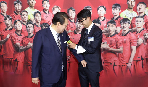 8일 축구 국가대표팀 환영 만찬에서 손흥민 선수(오른쪽)가 착용했던 주장 완장을 윤석열 대통령에게 채워주고 있다. <이승환 기자>