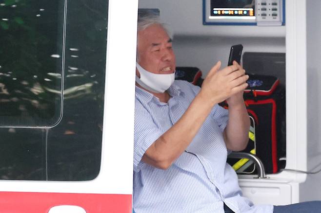 코로나19 확진 판정을 받은 사랑제일교회 전광훈 목사가 17일 오후 서울 성북구 사랑제일교회 사택을 나와 성북보건소 차량에 탑승해 마스크를 턱까지 내린 채 휴대전화를 보고 있다. 2020.8.17