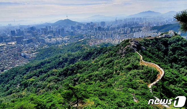 한양도성길. 돈의문 터에서 인왕산을 오르며 뒤돌아 본 풍경. 서울 시내와 남산-청계산-관악산을 배경으로 한양도성이 용처럼 꿈틀거리며 올라오는 풍경.