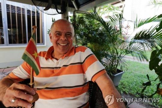 수리남 깃발을 들고, 오렌지색 상의를 입은 수리남 사람. [사진=연합뉴스]