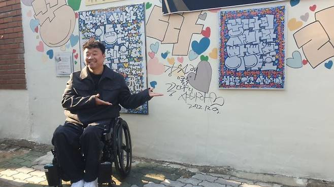 강원래 작가가 대구시 서구 인동촌 백년 마을 골목에 그려놓은 벽화를 설명하고 있다.