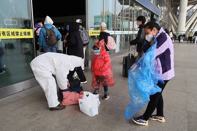 11일 중국 후베이성 우한의 기차역 앞에서 한 여성이 비옷을 방호복 삼아 입고 있다. 중국은 지난 7일 방역 정책을 대폭 완화하며 위드코로나 전환을 시도하고 있다./로이터 연합뉴스