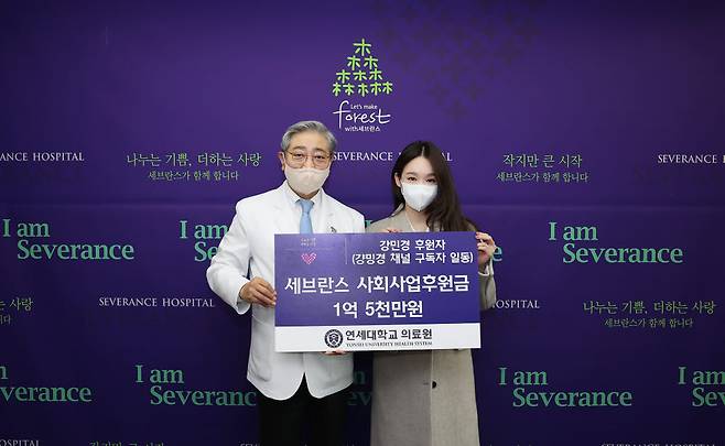 윤동섭 연세대학교 의료원장(왼쪽)과 가수 강민경 씨가 기부 판넬을 들고 기념 촬영을 하고 있다. (연세대의료원 제공)
