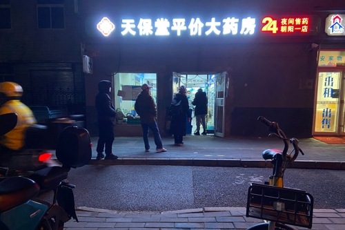 중국 베이징의 한 약국 앞에 지난 12일 저녁 약을 사려는 시민들이 줄을 서 있다.  AFP연합뉴스