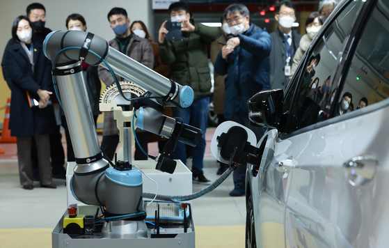 An automated robot charges an electric vehicle (EV) at a parking lot in Sejong during a robot test-run event held Wednesday attended by officials from the Ministry of Interior and Safety, and Sejong City Hall and experts from local robot manufacturers and universities. Self-driving cars were also presented on Wednesday, developed to function in underground parking lots where GPS doesn't work. [YONHAP]