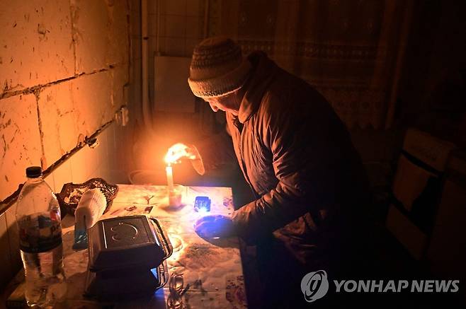 촛불 켜는 우크라이나 여성 (키이우 AFP=연합뉴스) 13일(현지시간) 우크라이나 수도 키이우의 한 마을에서 한 여성이 집에서 촛불을 켜고 있다. 2022.12.15 photo@yna.co.kr