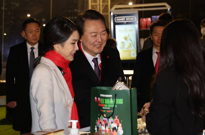 윤석열 대통령과 김건희 여사가 12월16일 오후 서울 종로구 열린송현광장에서 열린 윈·윈터 페스티벌 개막식에서 에어돔 부스를 방문, 물건을 구입하고 있다. ⓒ 연합뉴스