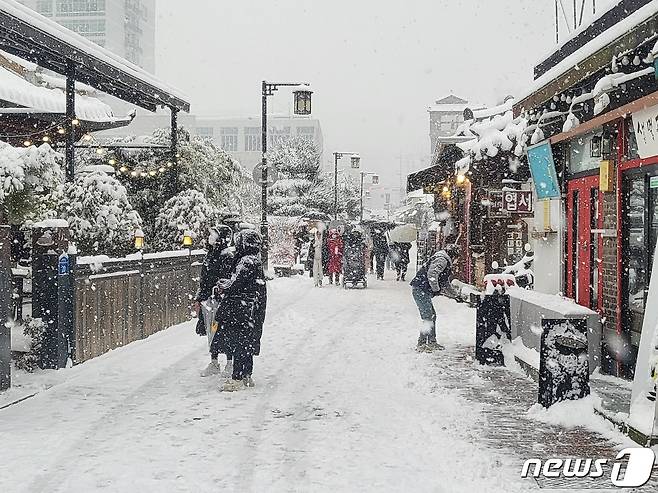 17일 눈이 내리는 전북 전주한옥마을에서 관광객들이 겨울 정취를 만끽하고 있다. 상인들은 매장 앞에 쌓여가는 눈을 치우는데 분주한 모습이었다.2022.12.17/뉴스1 ⓒ News1 강교현기자