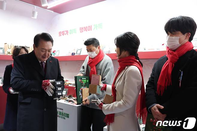 윤석열 대통령과 김건희 여사가 16일 오후 서울 종로구 열린송현녹지광장에서 열린 윈-윈터 페스티벌 개막식에 참석해 소상공인 상품 TOP 10 부스를 둘러보며 물건을 구입하고 있다. (대통령실 제공) 2022.12.16/뉴스1 ⓒ News1 안은나 기자