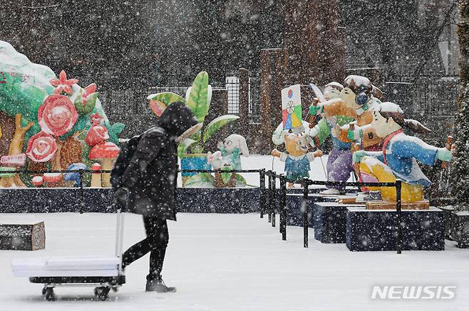 [서울=뉴시스] 권창회 기자 = 눈이 내리고 있는 15일 오후 서울 종로구 광화문에서 시민들이 모자를 쓰고 이동하고 있다. 2022.12.15. kch0523@newsis.com