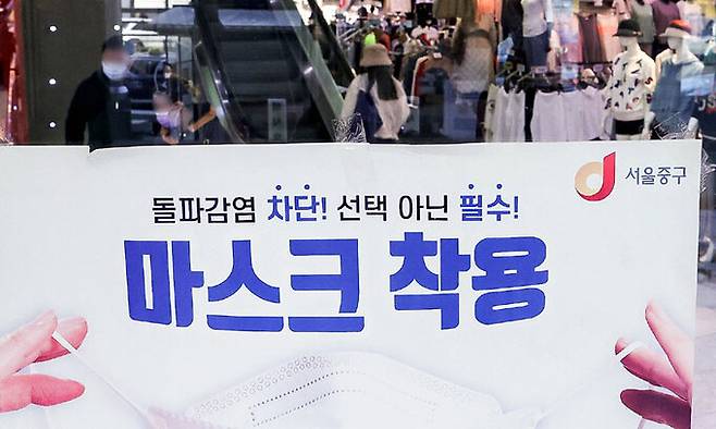 마스크 없는 일상 눈 앞에 18일 서울 시내의 한 대형 쇼핑몰에 마스크를 필수로 착용해달라는 안내문이 붙어 있다. 정부는 대중교통과 의료기관 등을 제외하곤 마스크 착용을 권고로 전환하고, 추이를 살펴본 뒤 착용 의무를 전면 해제하는 2단계 조정을 검토 중이다. 최상수 기자