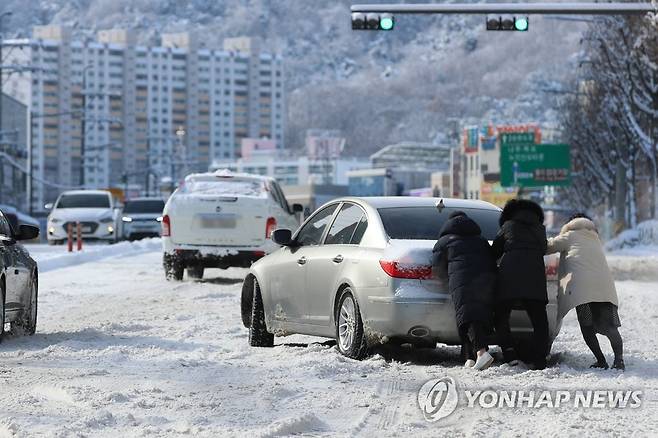 언덕길 낭패 (광주=연합뉴스) 천정인 기자 = 대설특보가 발령된 18일 오전 광주 남구 한 도로에서 시민들이 눈길을 빠져나가지 못하는 차량의 후미를 밀어주고 있다. 2022.12.18 iny@yna.co.kr