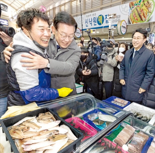 이재명 더불어민주당 대표(가운데)가 22일 고향인 경북 안동의 중앙신시장을 찾아 상인과 포옹하고 있다. 이 대표는 전날 저녁 수원지검 성남지청 형사3부로부터 피의자 신분으로 출석해 조사받으라는 통보를 받았다.  /뉴스1