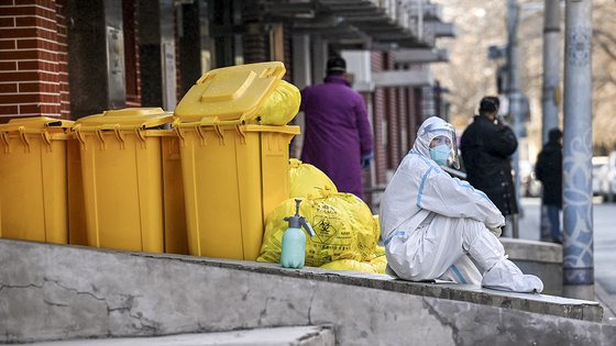 지난 19일 베이징 거리 한가운데 방역복을 입은 작업자가 주저앉아 있다. AFP=연합뉴스