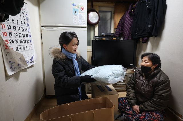 윤석열 대통령의 부인 김건희 여사(왼쪽)가 22일 서울 남대문 쪽방촌 어르신을 찾아가 식료품 등이 담긴 '희망박스'와 함께 겨울점퍼와 머플러를 전달하고 있다. 대통령실 제공.