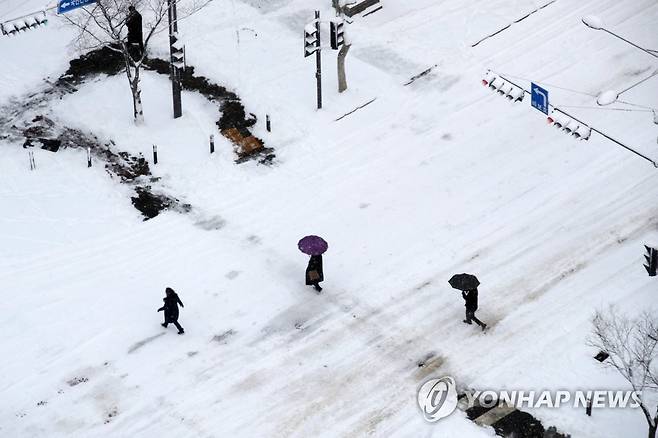 폭설에 덮인 도로 (광주=연합뉴스) 조남수 기자 = 대설경보가 발효된 23일 오전 광주 서구 치평동에서 시민들이 횡단보도를 건너고 있다. 2022.12.23 iso64@yna.co.kr