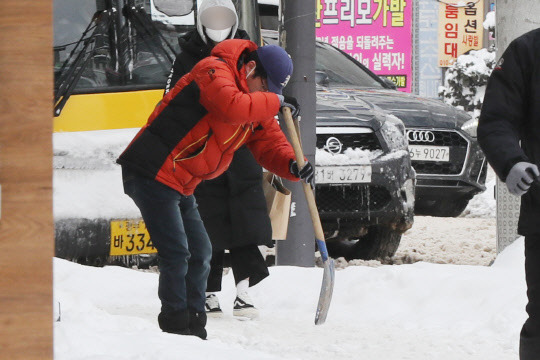 대설 특보가 해제된 24일 오전 광주 남구 봉선동에서 한 시민이 꽁꽁 언 눈을 삽으로 부수면서 치우고 있다. 연합뉴스