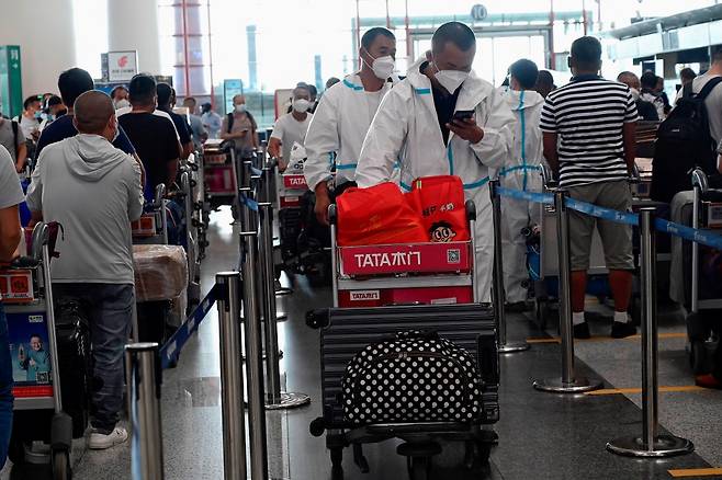 지난해 8월 코로나19 방호복을 입은 중국 여행객들이 베이징 공항에서 체크인을 위해 줄을 선 모습./AFPBBNews=뉴스1