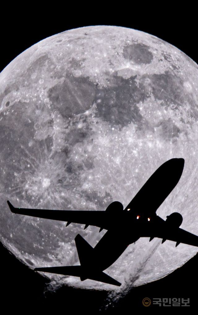 지난 7일 인천 서구에서 보름달이 보이고 있는 가운데 김포공항에서 이륙한 항공기가 달 앞을 가로지르고 있다.