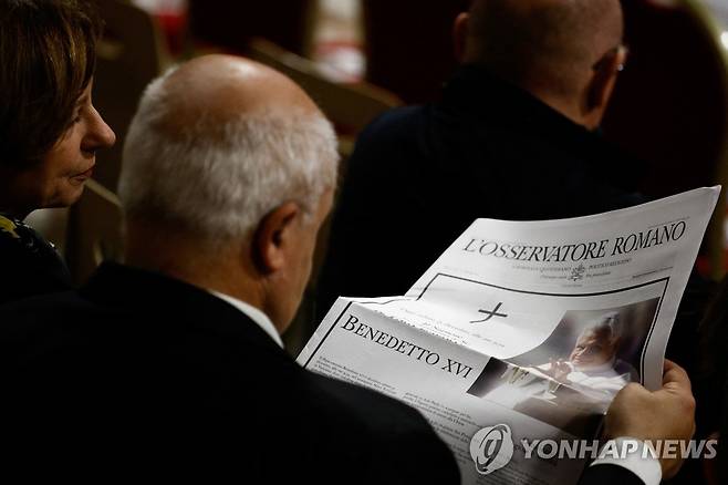 베네딕토 16세 전 교황 선종 (바티칸 로이터=연합뉴스) 31일(현지시간) 바티칸 성 베드로 대성전에서 한 신자가 베네딕토 16세 전 교황의 선종 소식을 담은 신문을 읽고 있다. 2022.12.31 photo@yna.co.kr