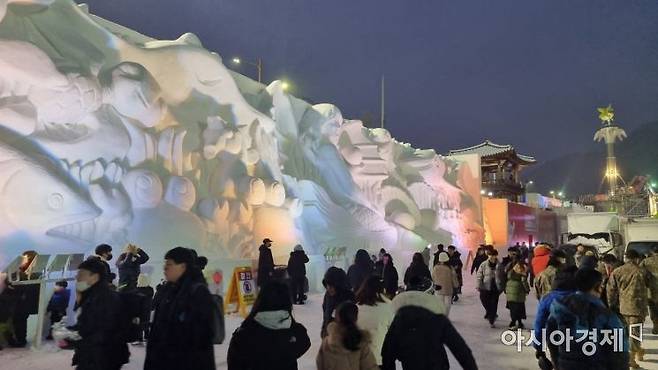 축제장에 설치한 빙벽 조각을 배경으로 관광객들이 기념촬영을 하고 있다 [라영철]