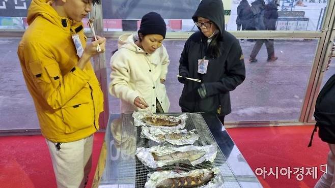 외국인들이 산천어 구이 맛을 즐기고 있다. [라영철]