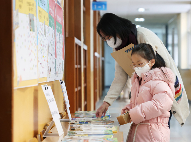 ▲26일 오후 경기도 수원시 장안구 송원초등학교에서 열린 신입생 예비소집에서 예비 초등학생이 엄마와 전시된 교과서를 살펴보고 있다. ⓒ연합뉴스