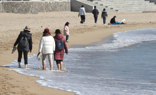 포근한 날씨를 보인 11일 오후 부산 송정해수욕장에서 시민들이 맨발로 해변을 산책하고 있다. (사진=연합뉴스)