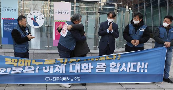 ​진경호 전국택배노조 위원장(왼쪽 둘째)이 12일 오후 서울 서초구 서울행정법원 앞에서 씨제이대한통운의 원청 사용자성 행정 소송 1심 선고에 대한 약식 기자회견을 마친 뒤 박석운 전국민중행동 공동대표와 끌어안으며 기뻐하고 있다. 윤운식 선임기자 yws@hani.co.kr