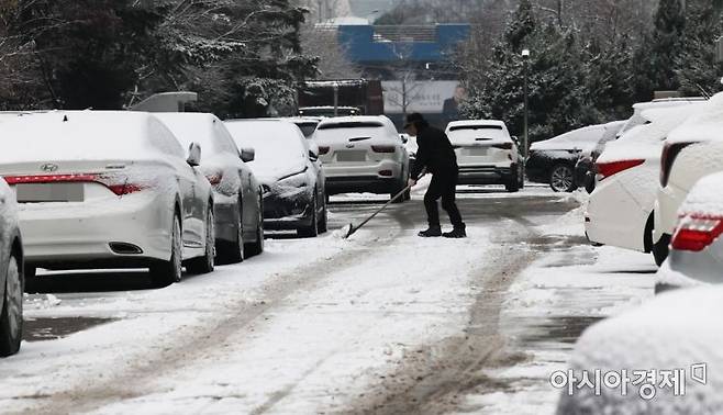 서울을 비롯해 중부지방에 대설특보가 발효된 21일 서울 시내 한 아파트 단지 내에 아파트 관리인이 주차장에 쌓인 눈을 치우고 있다./윤동주 기자 doso7@