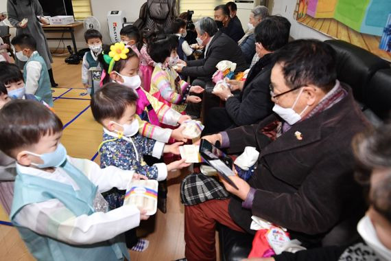 설 연휴를 앞둔 17일 오전 서울 송파구 문정 래미안 아파트 경로당에서 삼성아트 어린이집 원생들이 합동 세배를 마친 후 어르신들에게 떡을 전달하고 있다. 사진=서동일 기자