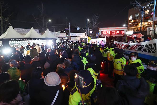 25일 오후 서울 용산구 녹사평역 광장에 마련된 이태원참사 희생자 시민분향소에서 시민들이 천주교 정의구현전국사제단 주최 참사 희생자와 유가족을 위한 성탄대축일 미사를 기다리는 가운데(왼쪽) 보수 단체가 집회를 하고 있다. 연합뉴스