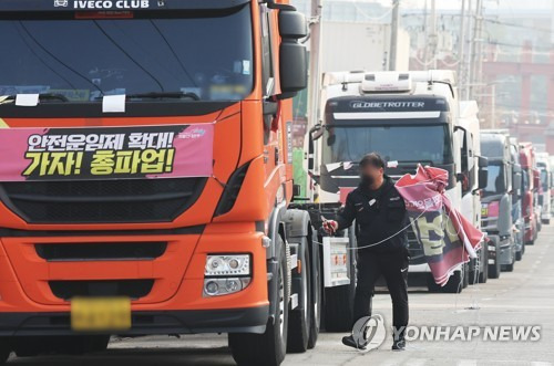 화물연대가 파업을 종료하고 현장 복귀를 결정한 지난해 12월 9일 오후 경기도 의왕시 내륙컨테이너기지(ICD) 앞에서 관계자가 도로에 세워둔 화물차들에 붙어있던 파업 관련 현수막을 철거하고 있다. 연합뉴스