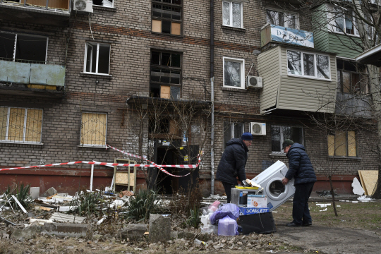 지난 16일(현지시간) 우크라이나 남부 자포리자에서 한 다가구주택 주민들이 전날 밤 러시아군 로켓공격에 파손된 주택에서 짐을 꺼내 떠나고 있다. AP 연합뉴스