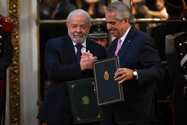 루이스 이나시우 룰라 다시우바(왼쪽) 브라질 대통령과 알베르토 페르난데스 아르헨티나 대통령이 23일(현지 시간) 부에노스아이레스 대통령궁에서 정상 합의문에 서명한 후 손을 맞잡고 있다. AFP연합뉴스