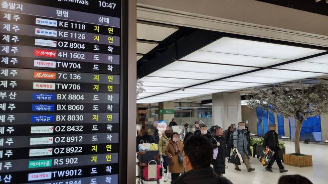 25일 오전 김포공항 도착 게이트를 빠져나가는 승객들 옆에 항공기 도착 '지연'을 알리는 문구가 표시돼 있다./채민석 기자