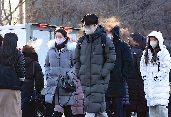 Pedestrians walk at Gwanghwamun Square in Seoul, Wednesday morning, as a cold wave warning was issued across the country. (Yonhap)