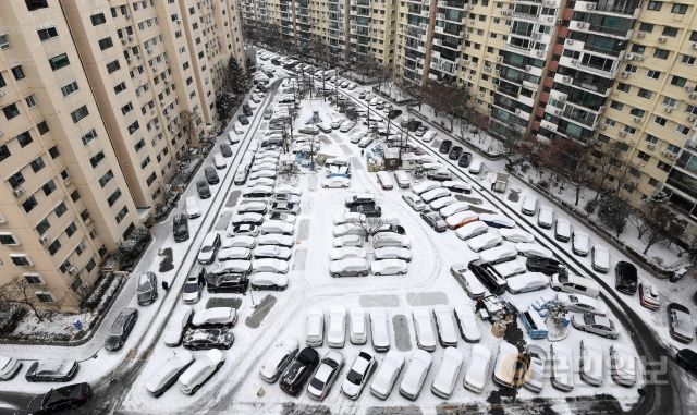 서울 등 중부지방을 중심으로 많은 눈이 내린 26일 서울에 위치한 한 아파트 단지에 시민들이 대중교통을 이용하여 차량들이 눈이 쌓인 채 주차되어 있다.