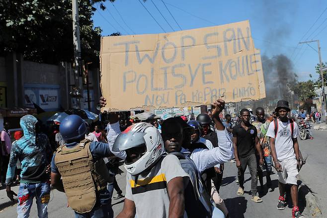 아이티의 수도 포르토프랭스에서 경찰관들의 폭동이 벌어진 가운데 한 시위 참가자가 “경찰이 너무 많은 피를 흘리고 있다. 더이상 참을 수 없다”는 피켓을 들고 있다. [로이터 연합]