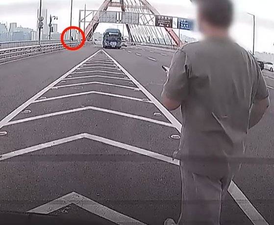 지난해 11월 12일 서강대교 난간에 앉아있는 20대 여성 B씨를 발견한 제보자 A씨가 B씨를 향해 걸어가고 있다. 사진 유튜브 채널 '한문철 TV' 캡처