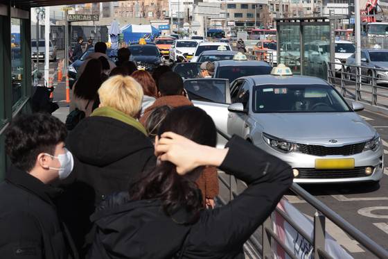 People wait in line to grab a taxi in front of Seoul Station in central Seoul on Sunday. The basic taxi fare in Seoul will be raised to 4,800 won ($3.9), up 1,000 won, starting Feb. 1. [YONHAP]