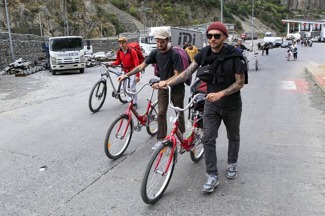 지난 28일(현지시간) 러시아인들이 자전거를 끌고 조지아 국경을 넘고 있다. AP=연합뉴스